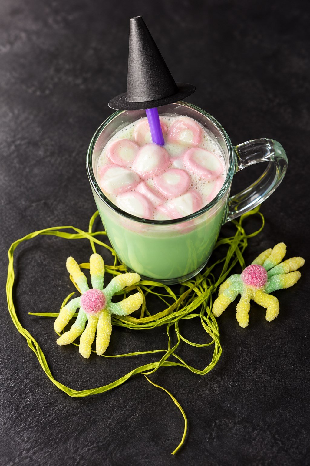 Vista de la bebida verde de chocolate blanco con nubes rosas y gominolas de araña