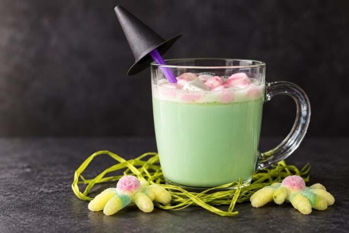 Brebaje de la bruja de chocolate blanco caliente con nubes rosas en una taza de cristal