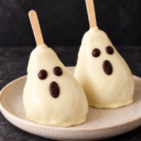 Dos peras fantasmas para Halloween cubiertas de chocolate blanco y decoradas con caras de chocolate negro