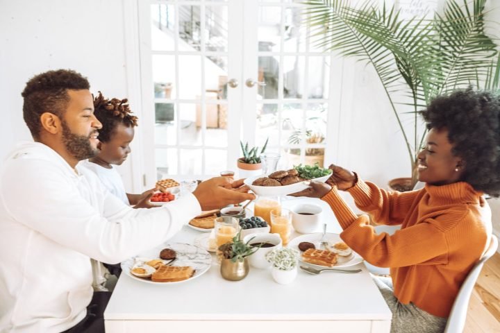 familia contenta compartiendo comida al rededor de una mesa